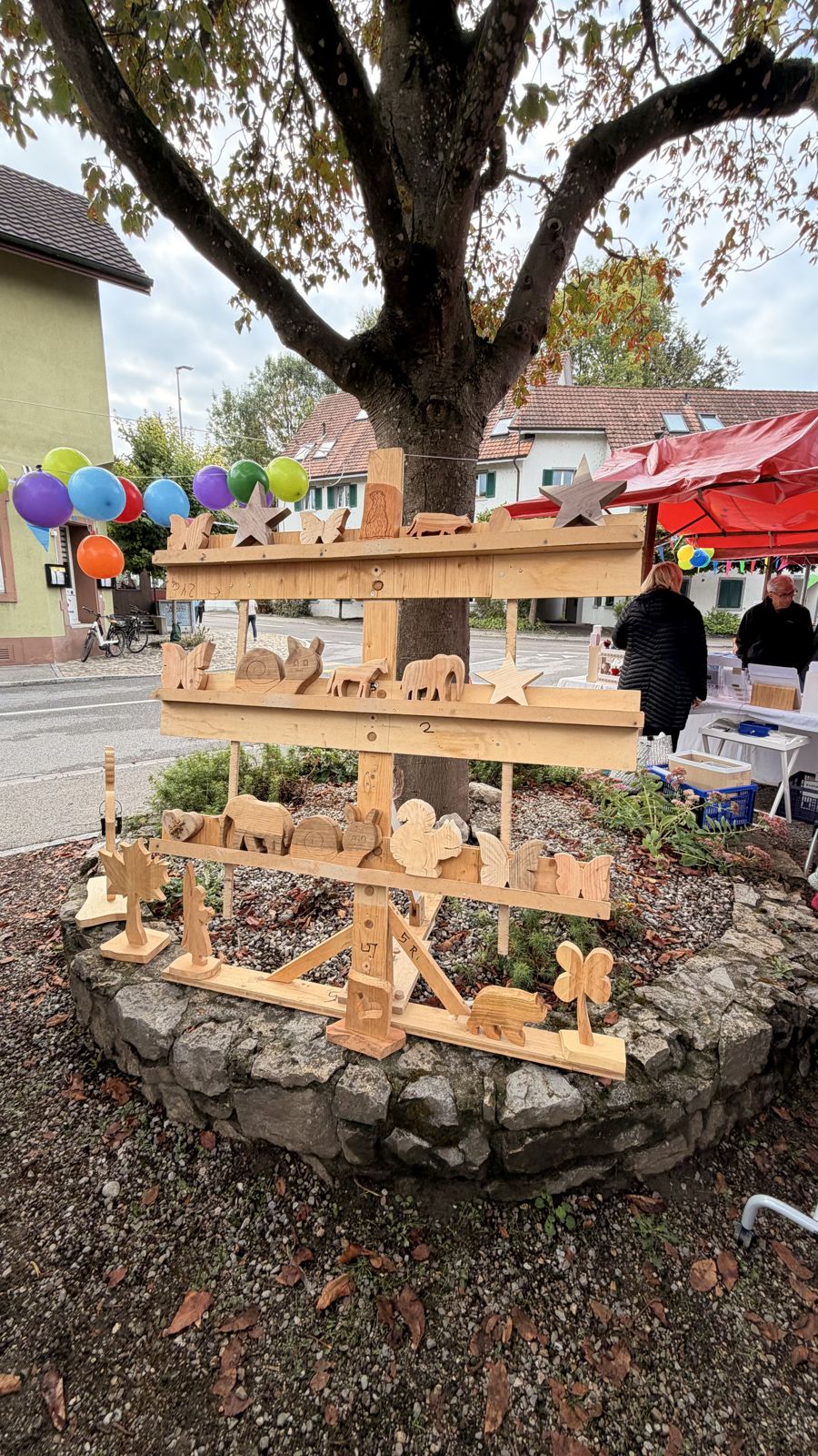 Herbschtmärt 2026 rund ums Melihus: Holzfiguren unter dem Baum